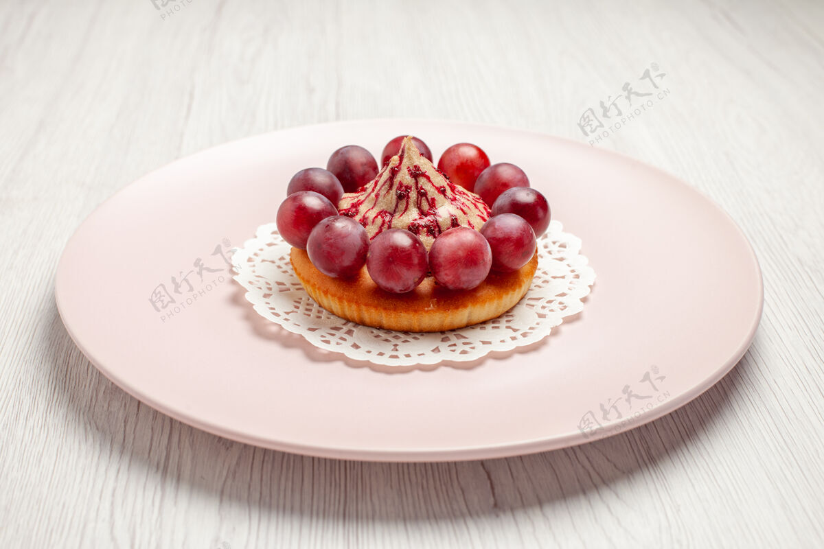 背景正面图：白色背景 盘子里有葡萄的小蛋糕葡萄里面水果