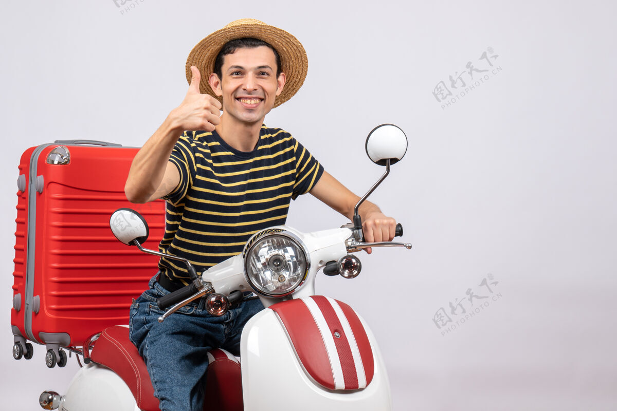 传送带一个戴着草帽的年轻人在轻便摩托车上竖起大拇指给予稻草车辆