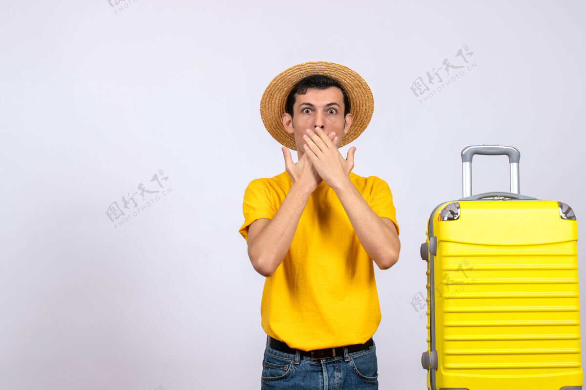 站立正面图：年轻的游客站在黄色手提箱旁 手放在嘴上嘴人前方