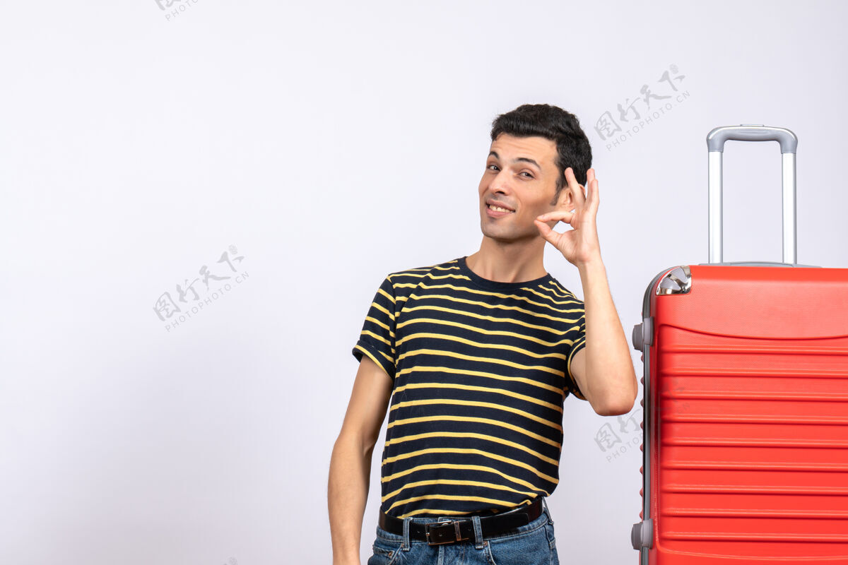年轻人正面图：一个穿着条纹t恤和红色手提箱的年轻人正在做一个ok的标志微笑视图人