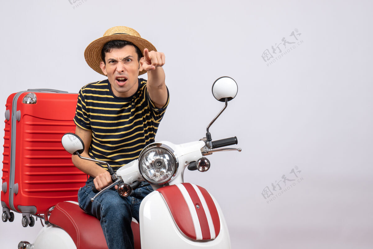 汽车前视图：一个戴着草帽的年轻人指着镜头人男人汽车