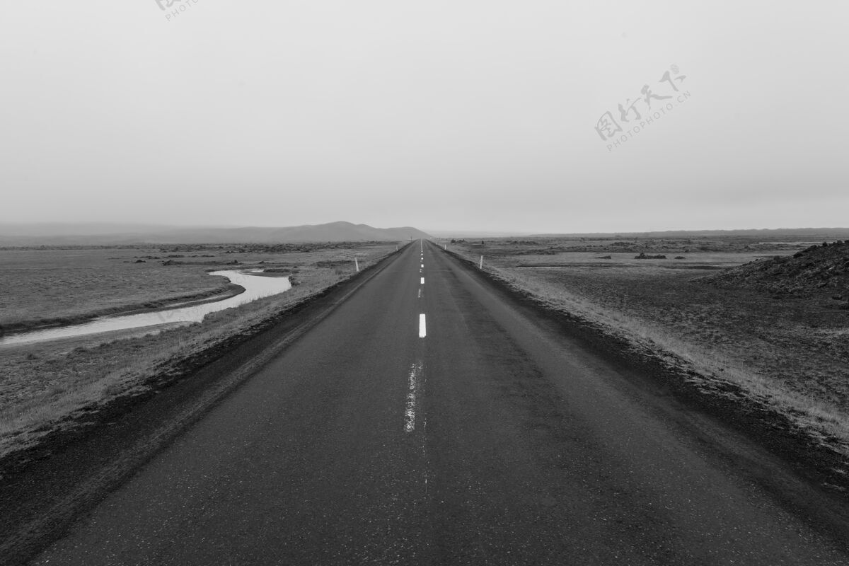 雾灰蒙蒙的一条道路在一片空旷的田野中间 阴云密布的天空下美景天