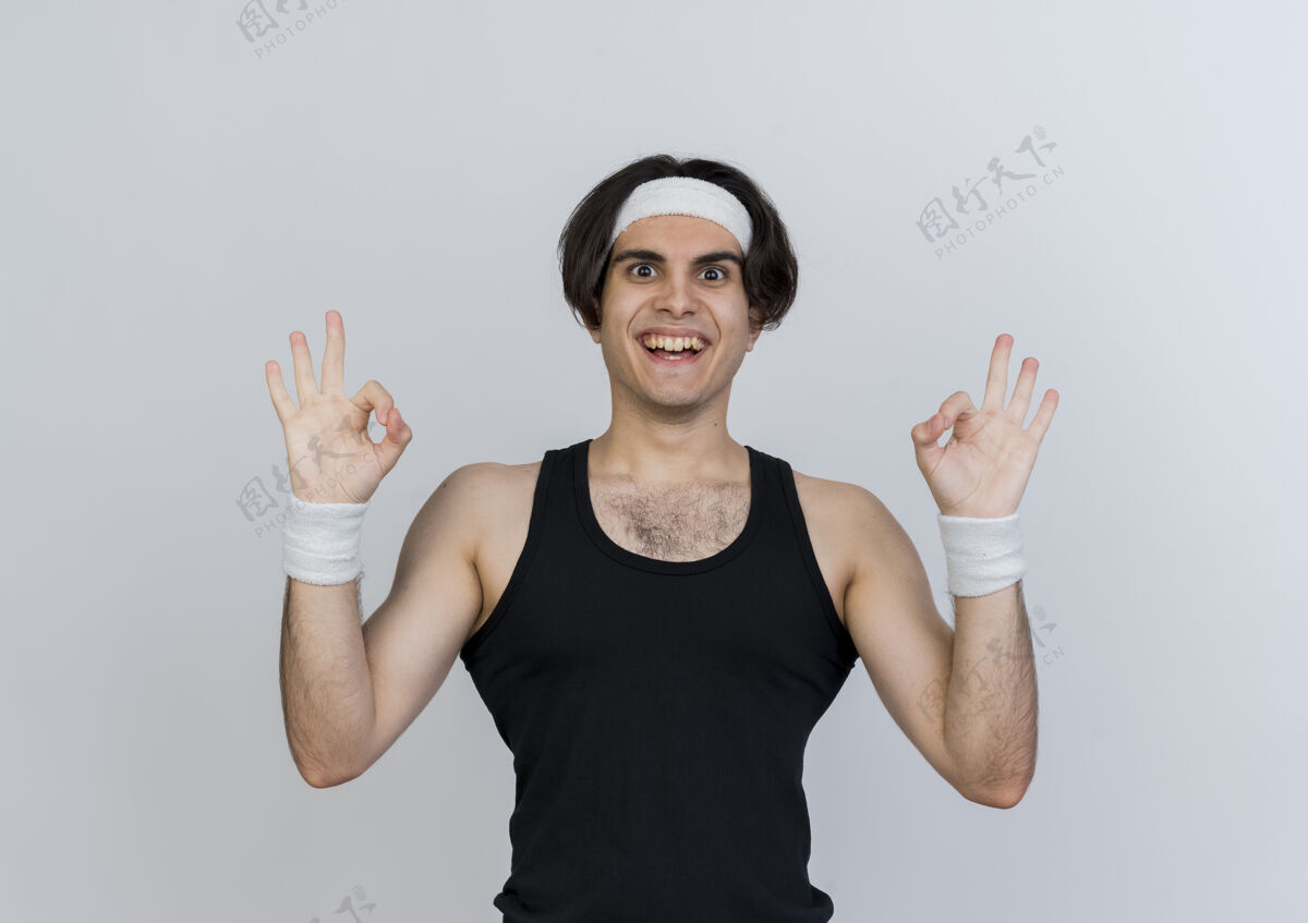 脸身穿运动服 头戴头巾的年轻人站在白色的墙上 面带微笑 脸上挂着ok标志人Ok微笑