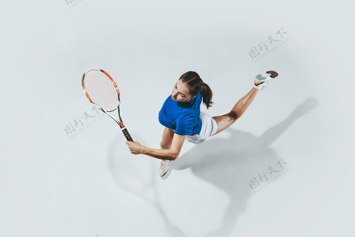 女孩穿蓝衬衫打网球的年轻女子她用球拍击球顶视图强壮运动成年人