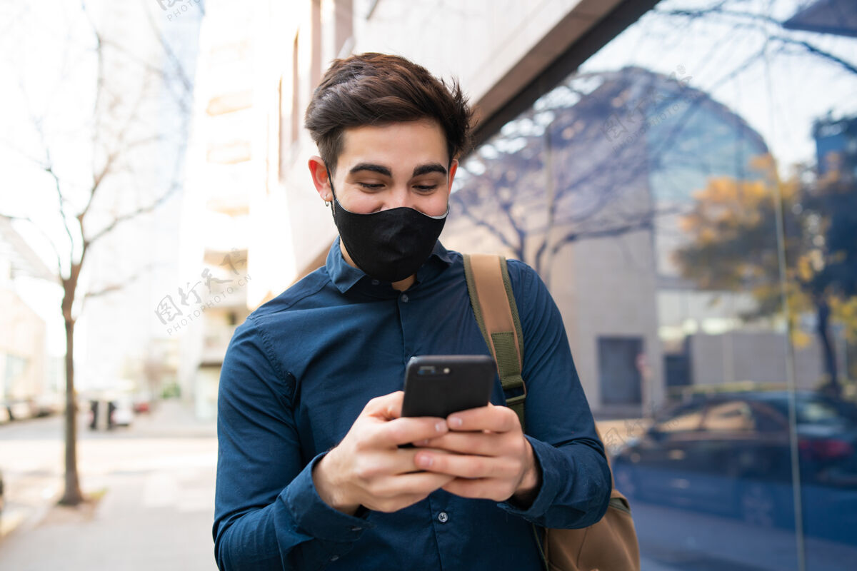 人一张年轻人在街上走在户外用手机的照片面具男性脸