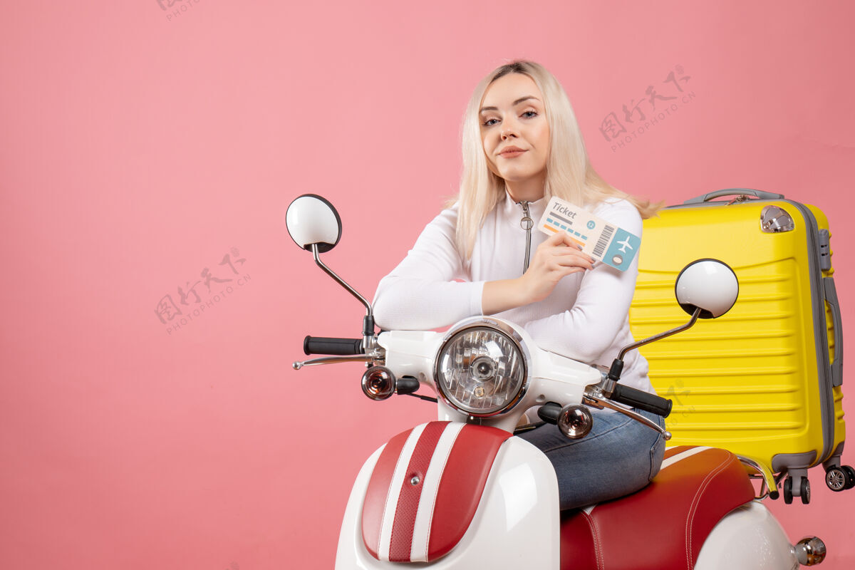 成人正面图：骑着轻便摩托车的年轻女士 带着黄色手提箱 手里拿着车票摩托车坐着微笑