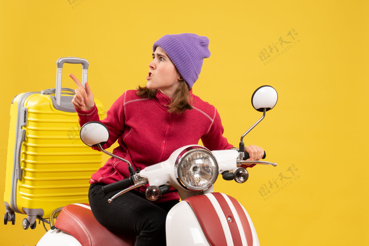 车辆前视图：骑着轻便摩托车的年轻女孩指着左手左边摩托车前面