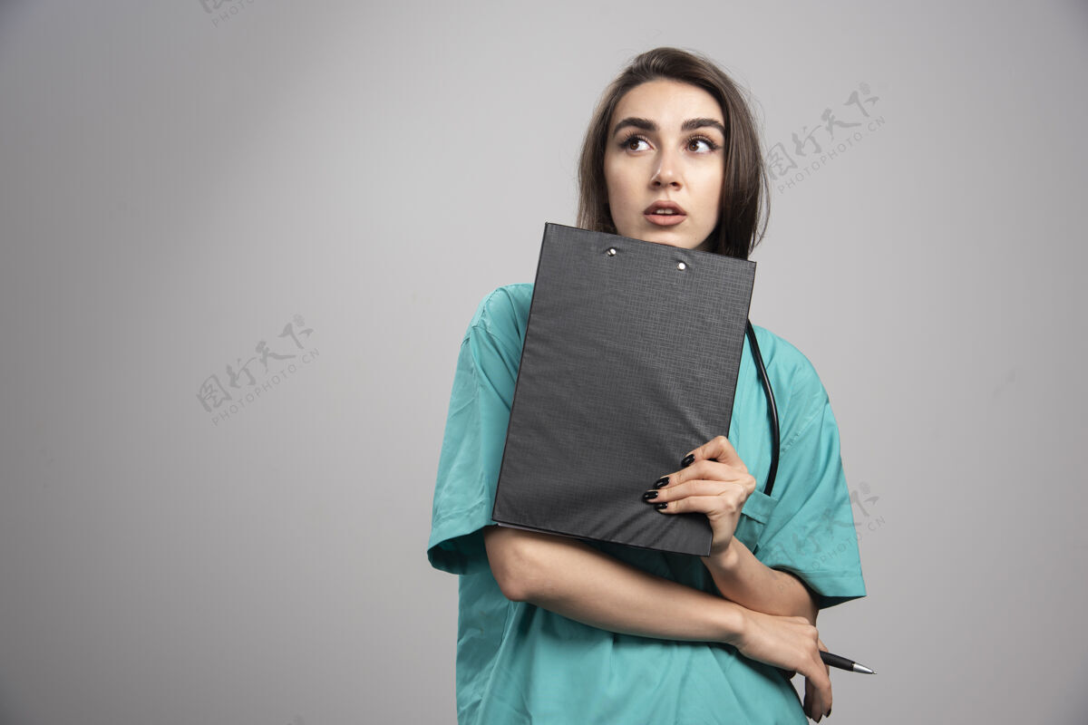 听诊器女医生摆姿势与剪贴板上的灰色背景高品质的照片检查制服女性