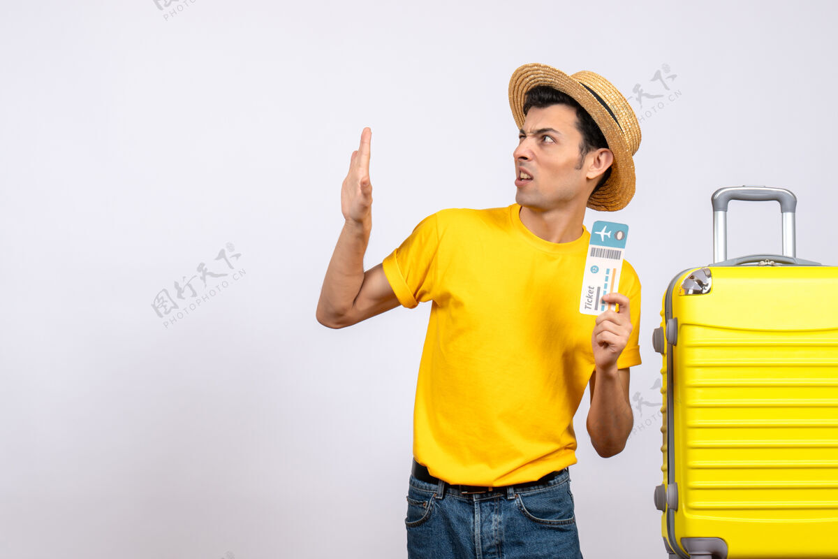T恤正面图身穿黄色t恤的年轻人站在黄色手提箱旁举着车票票人站立