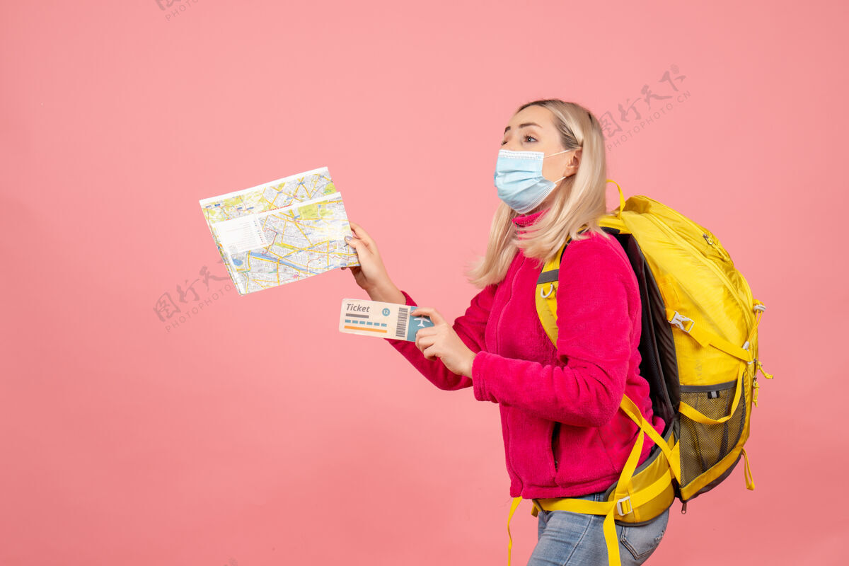 使正面图：一个背着黄色背包 戴着面具 拿着地图和车票的女游客女旅客快乐持有