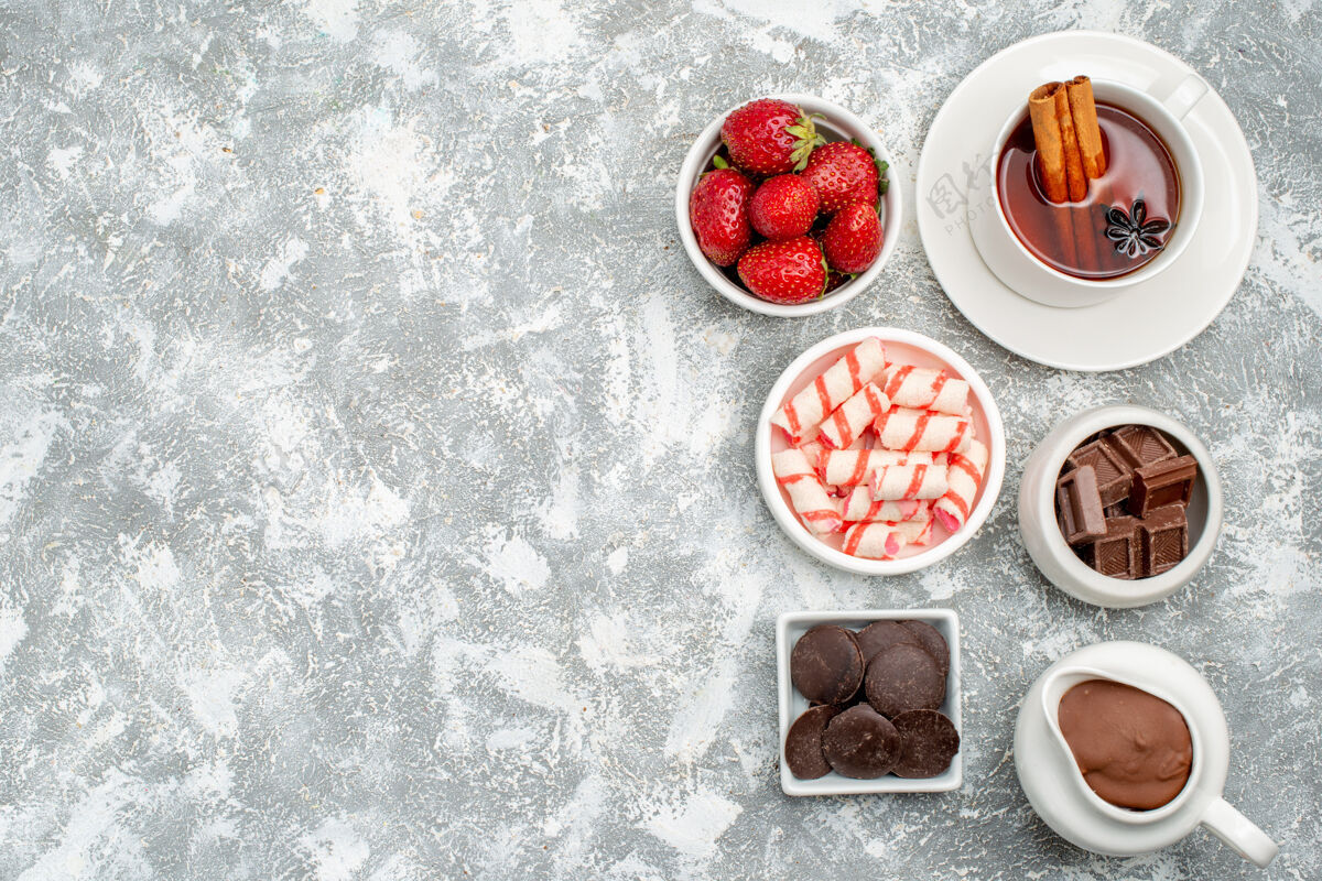 糖果顶视图饼干草莓可可和巧克力和茶与肉桂在右边的灰白色的桌子甜点桌子新鲜