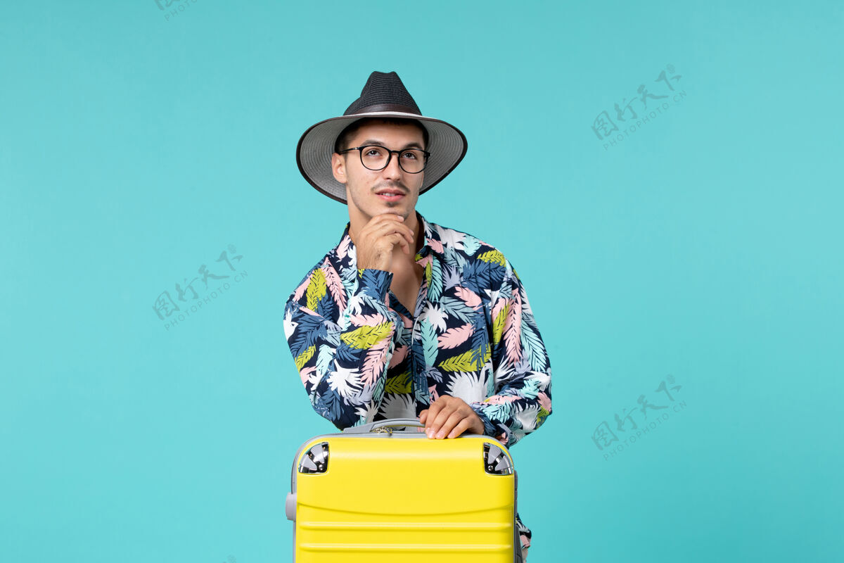 微笑年轻男子背着他的黄色袋子正准备在蓝色的墙上思考工人男人航行
