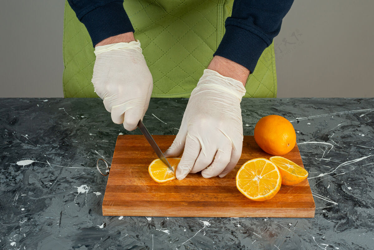 有机男性手戴手套在大理石桌上切橘子汁各种男围裙