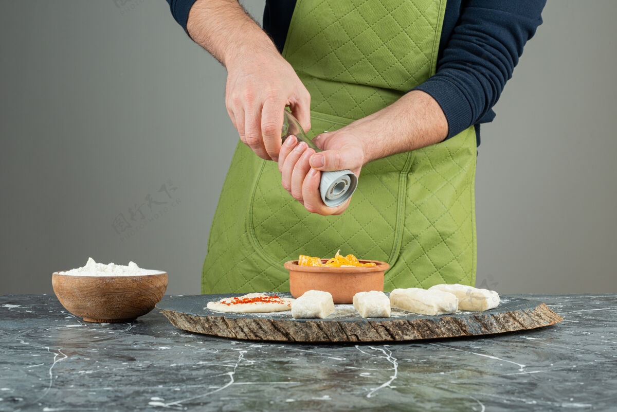 苹果男性手戴手套在大理石桌上的面团里加盐切片切有机
