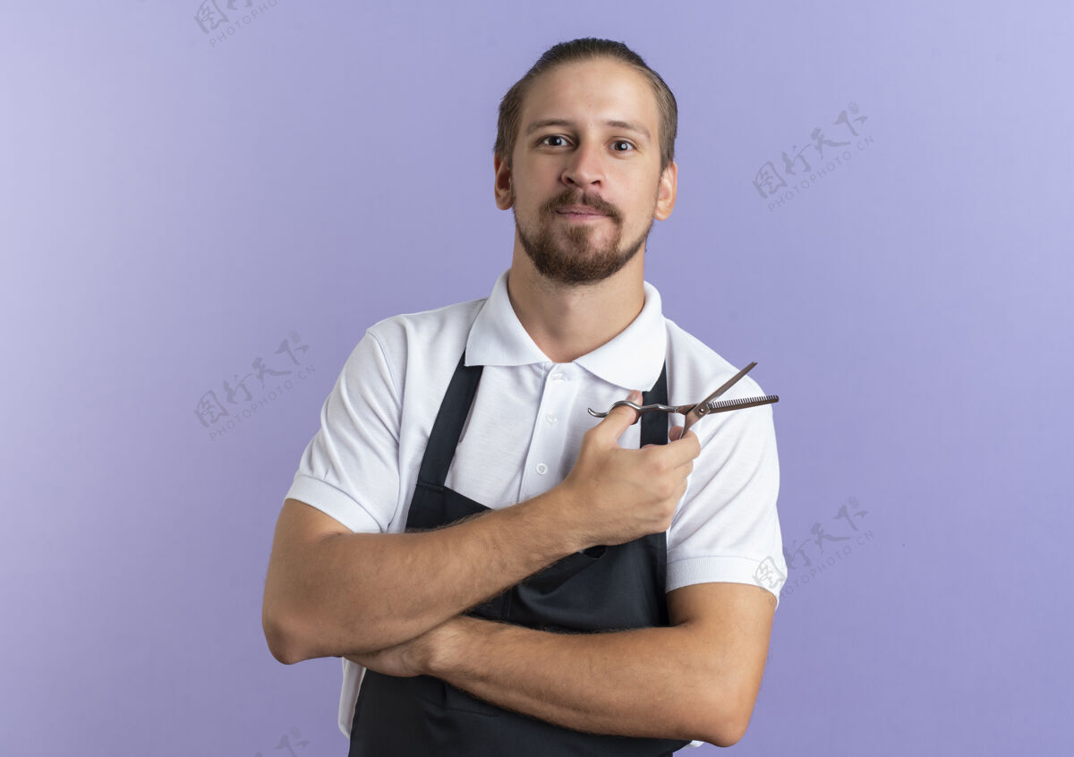 紫色高兴的年轻帅哥理发师穿着制服拿着剪刀隔离在紫色的墙上人衣服年轻
