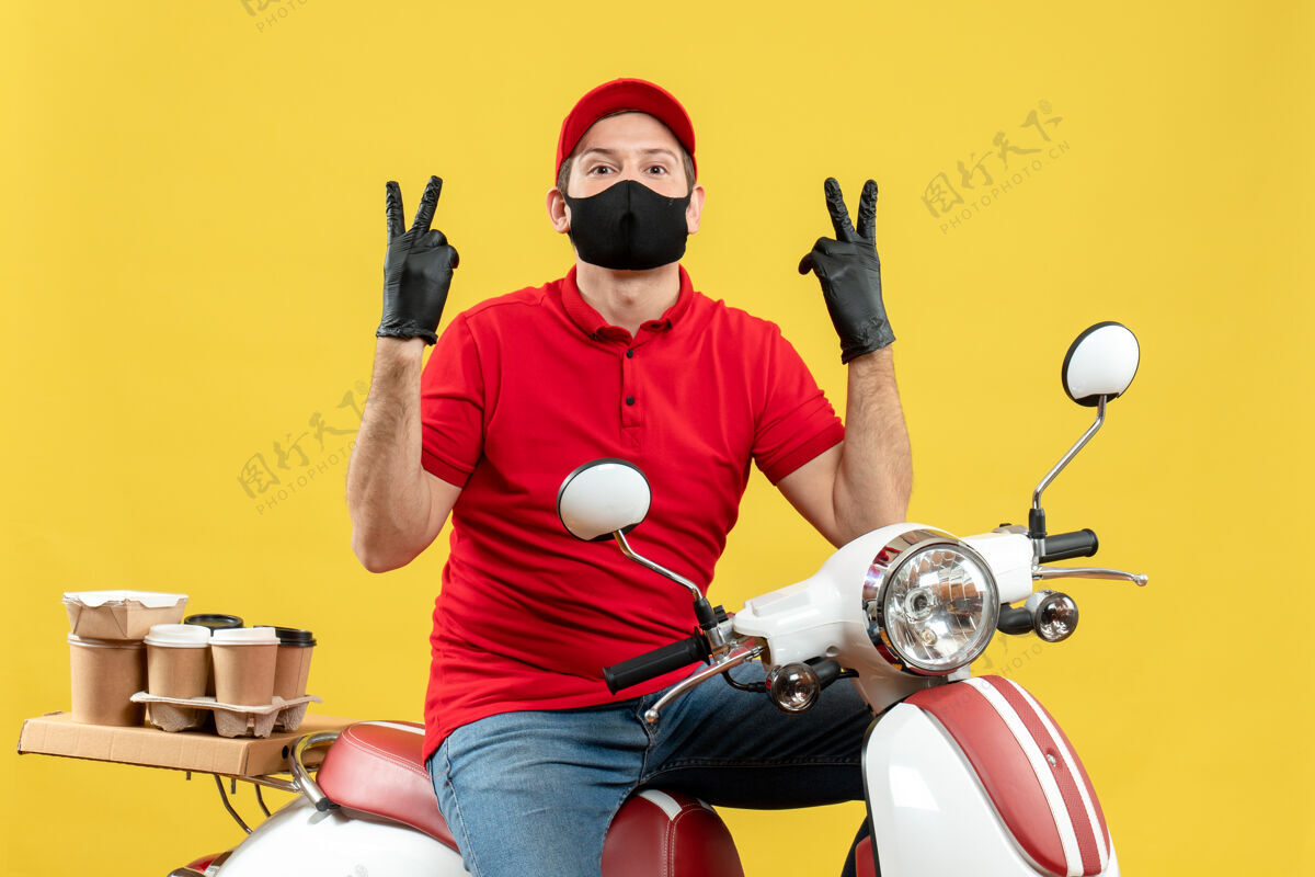 医疗俯视图：快递员身穿红色上衣 戴着帽子手套 戴着医用面罩 坐在滑板车上做着胜利手势摩托车摩托车手套