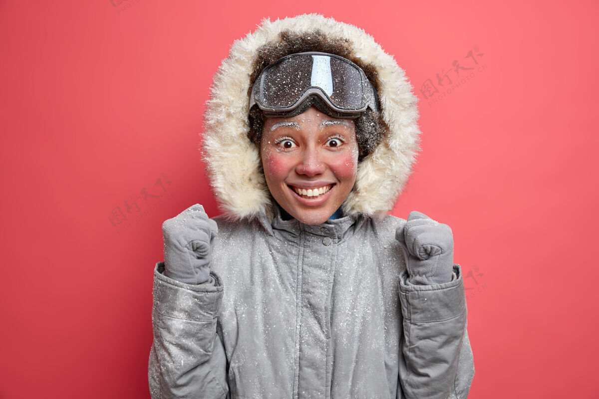 霜冻情绪积极的女人举起拳头 迫不及待地去滑雪板表达快乐的情绪享受冬天的时间和积极的休息穿暖和的夹克和滑雪镜快乐的女滑雪者人类心情温度
