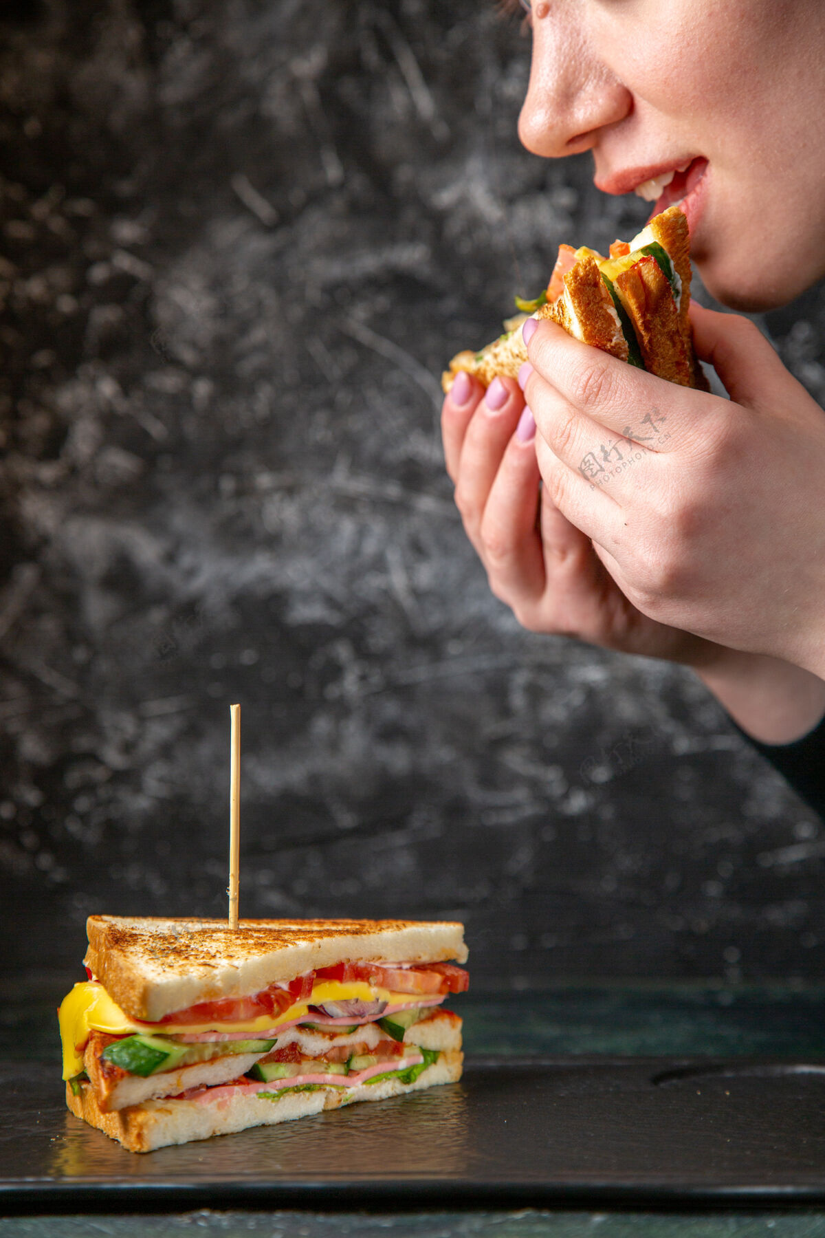 午餐正面图美味的火腿三明治正在黑暗的表面被女性吃掉前面食物女人