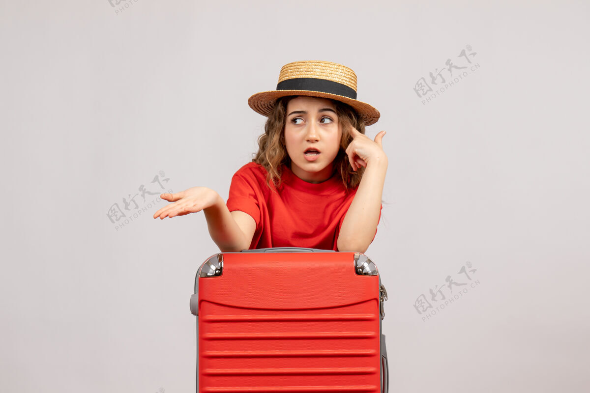 节日困惑的度假女孩正站在白色的墙上 手里拿着她的手提箱站欢呼成人