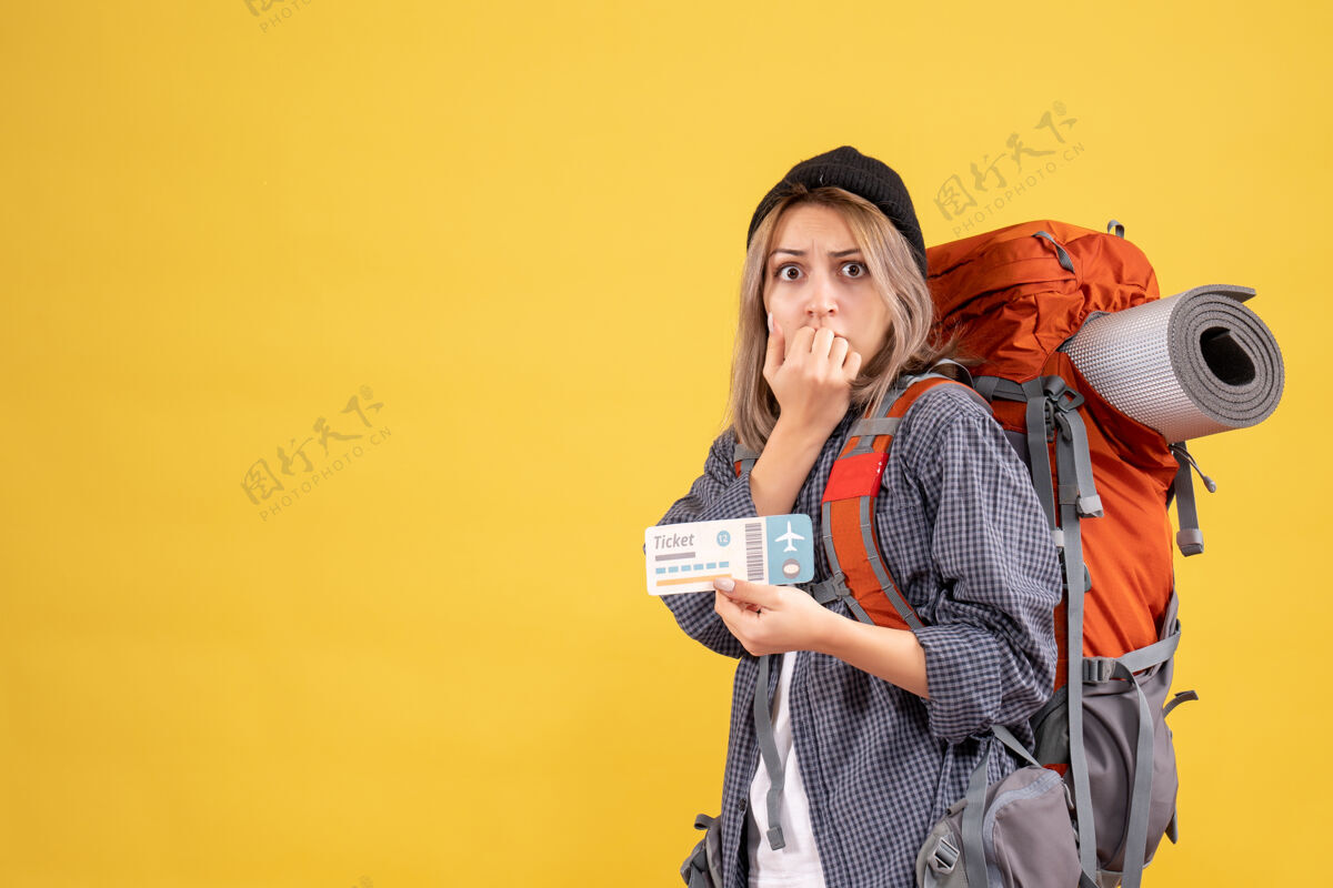 快乐焦躁不安的女旅客背着背包拿着车票的正面图前面肖像成人