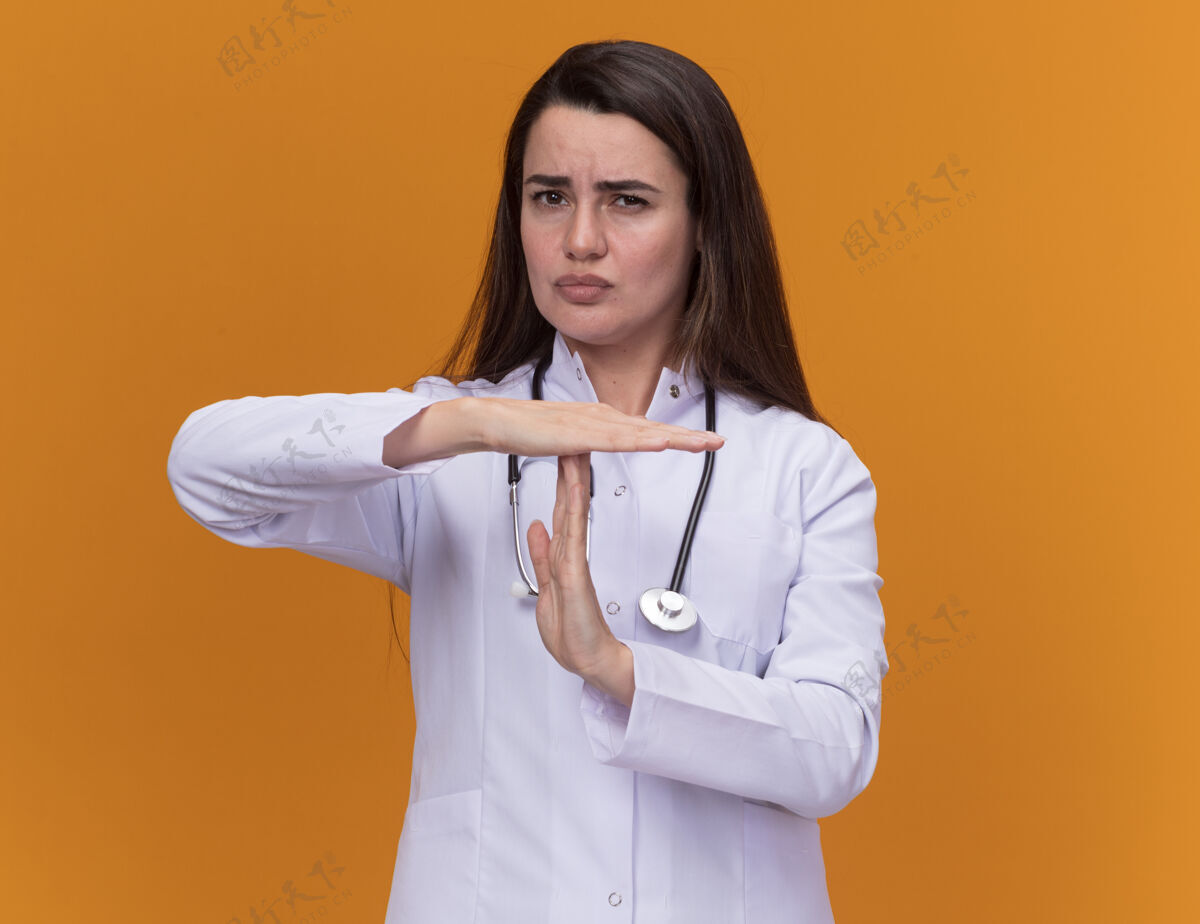 医学自信的年轻女医生穿着医用长袍带听诊器手势暂停橙色标志医生女性姿态