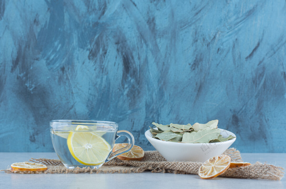 碗柠檬水和干柠檬片放在一碗叶子旁边 毛巾放在大理石上好吃的叶子美味