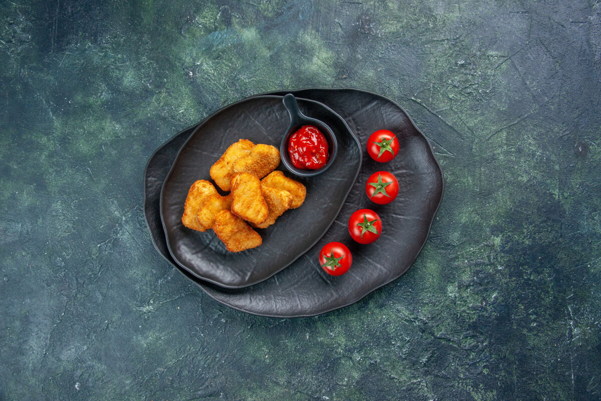 煎锅黑色盘子里的鸡块和番茄酱番茄的俯视图平底锅晚餐番茄酱