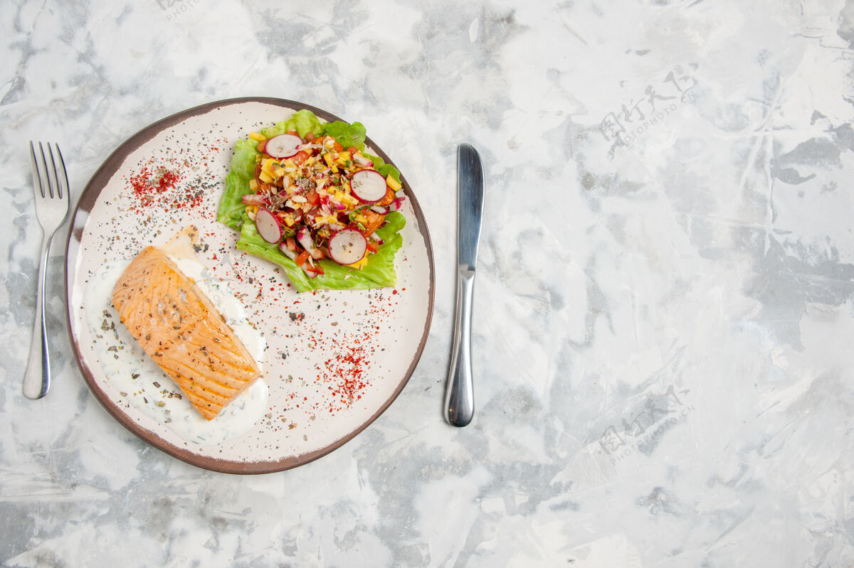 午餐鱼粉和美味沙拉的顶视图 盘子和餐具放在染色的白色表面左侧食物左侧晚餐