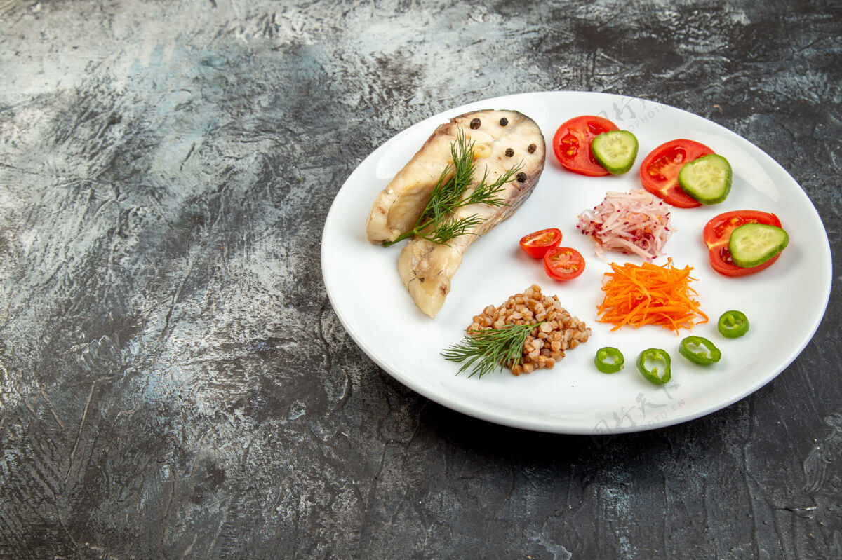 一餐冰面上白色盘子上的煮鱼荞麦和绿色蔬菜的侧视图午餐晚餐蔬菜