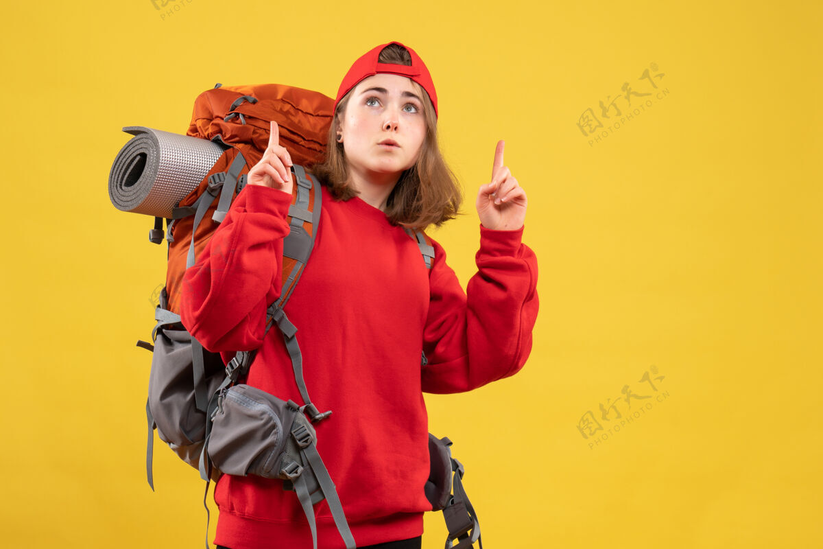 男人正面图很酷的女旅行者 背着背包 手指朝上成人前面指尖