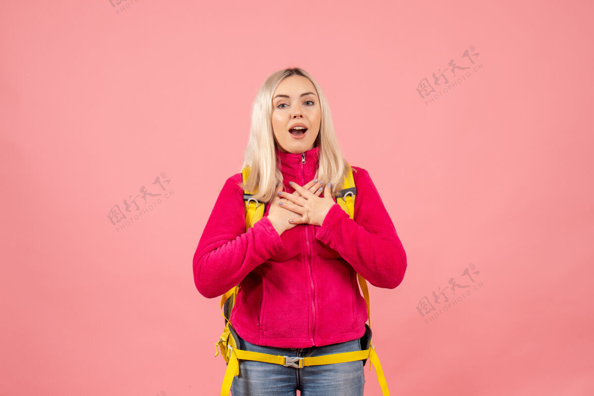 成人正面图金发女旅行者和她的背包站在粉红色的墙上时尚模特肖像