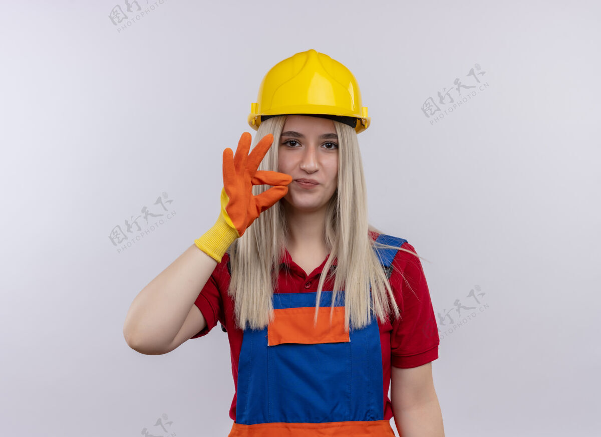 金发高兴的年轻金发工程师建设者穿制服的女孩戴着手套在孤立的白色空间与复制空间做ok标志女孩空间工程师