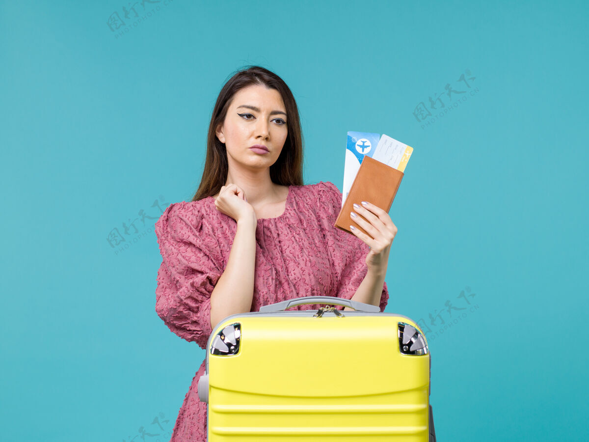 钱包前景度假中的女人拿着她的钱包和机票在蓝色的背景下旅行度假旅行的女人夏天的海前面持有旅行