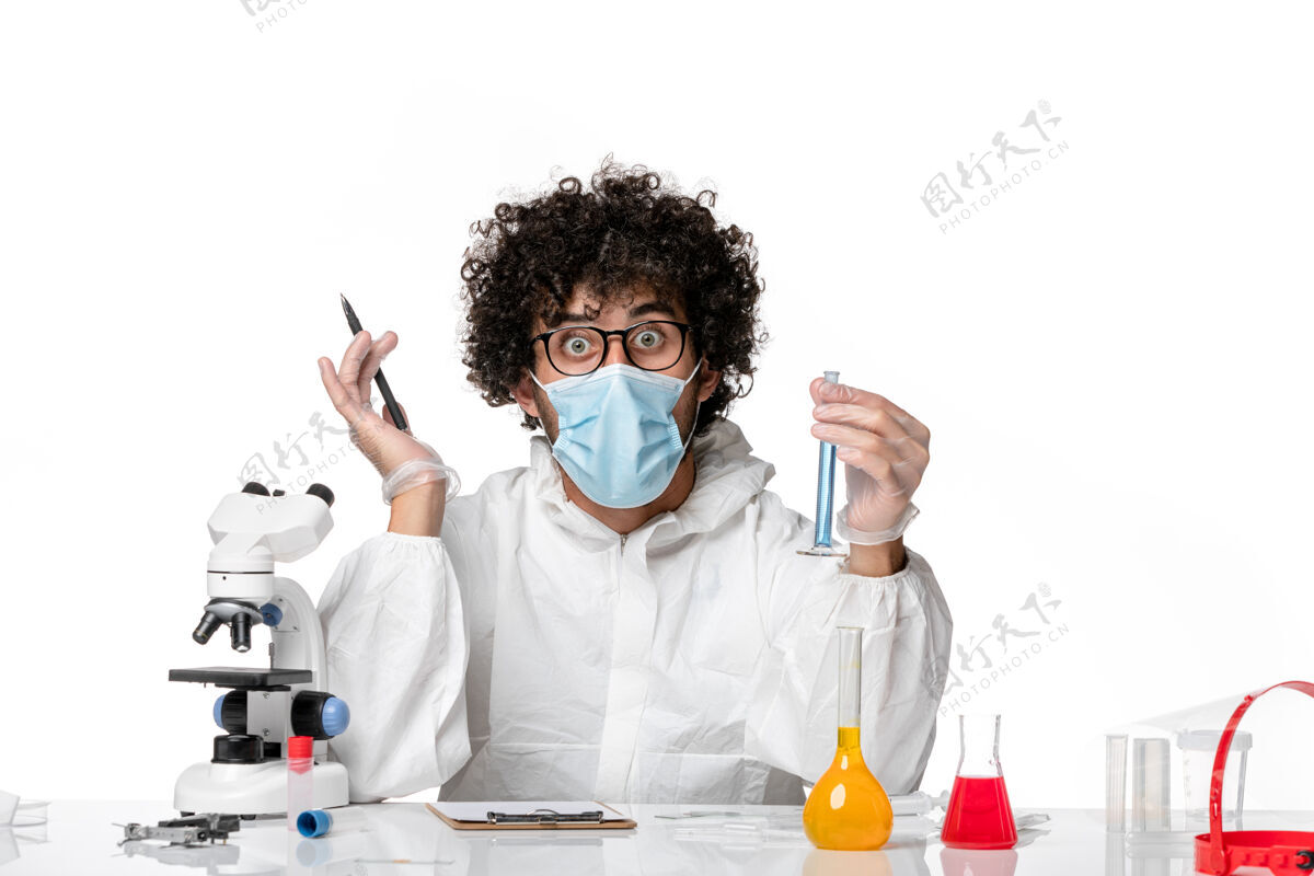 浅色正面图：男医生穿着防护服 戴着口罩 拿着浅白色背景上的蓝色溶液瓶——流行性病毒保温瓶白色蓝色