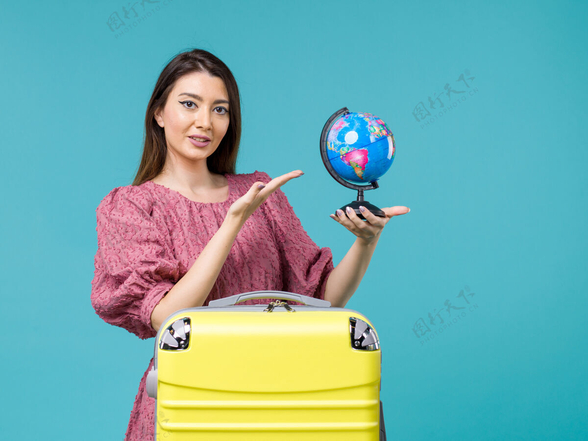 地球前景度假女抱着蓝色背景上的小地球仪出海度假旅行避暑女蓝色假期旅行