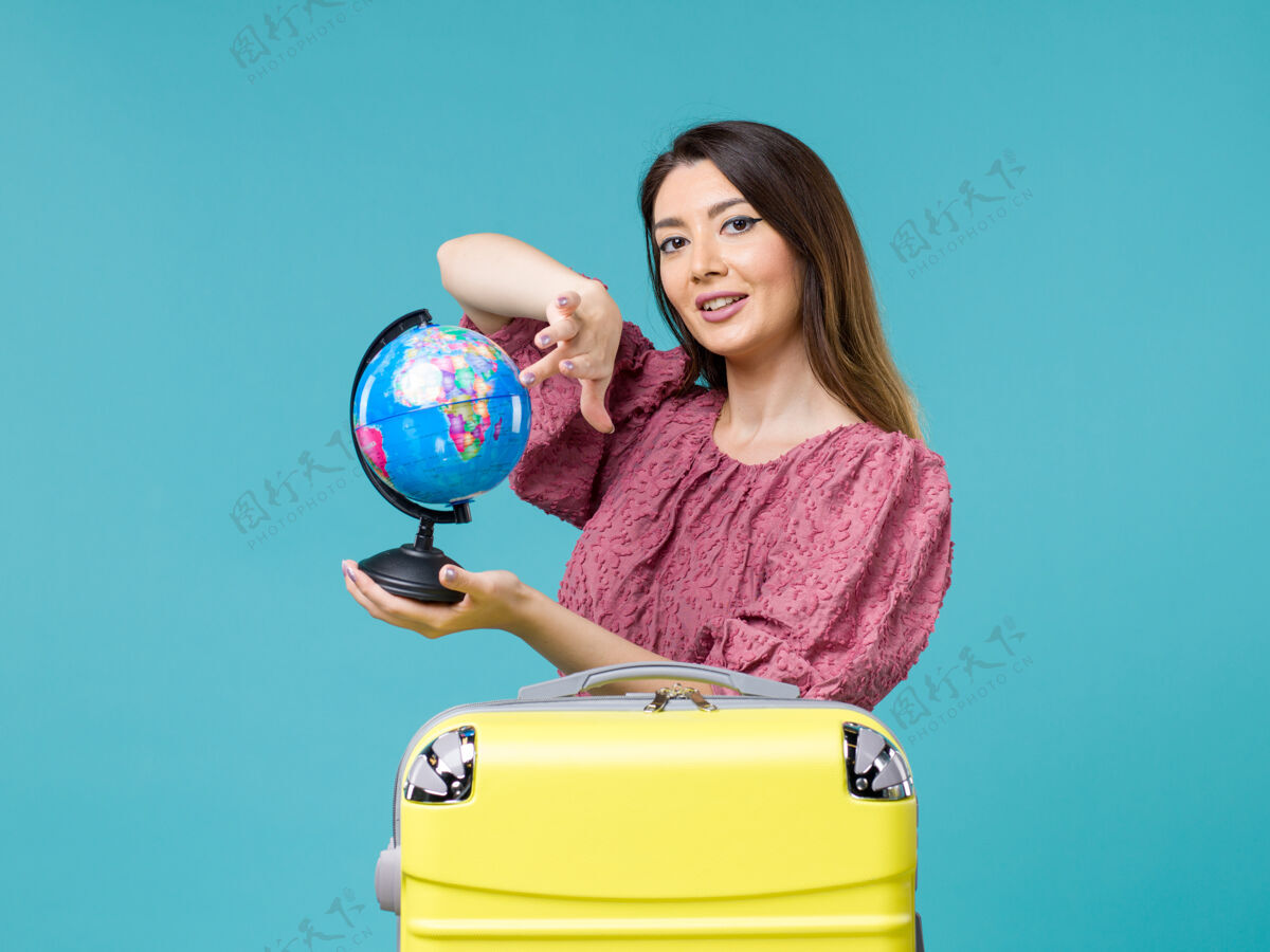蓝色前景度假女拿着蓝色地板上的地球仪海上度假女旅行暑假旅行地球仪微笑