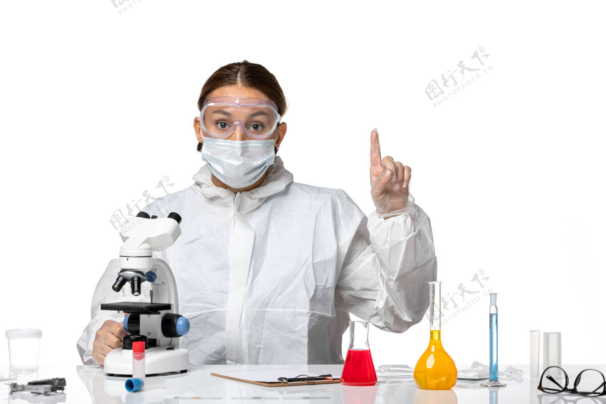 女医生正面图女医生穿着防护服 戴着口罩 用显微镜观察白色背景健康大流行病毒冠状病毒大流行正面健康