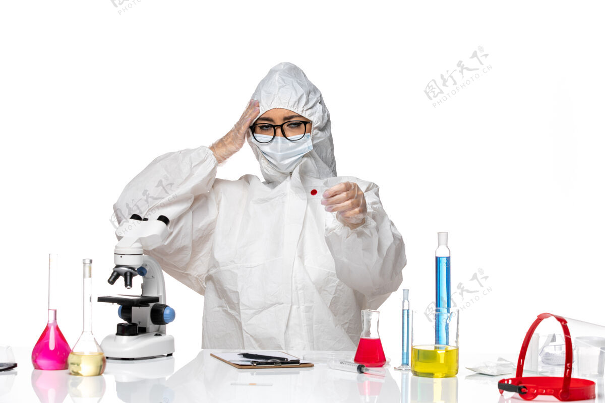 人正面图：穿着特殊防护服的女化学家正在检查白桌子上的样本病毒化学冠状病毒-大流行健康专业医疗桌子