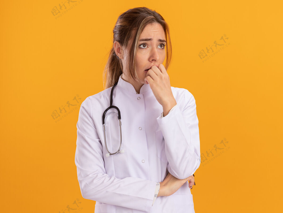 听诊器关心地看着身边年轻的女医生穿着医用长袍 手放在黄色的墙上隔离着的嘴上的听诊器公民人脸