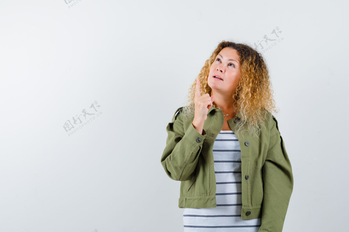 奇迹一个金发卷曲的女人 穿着绿色夹克 朝上看 脸上露出疑惑的神色女性女士人