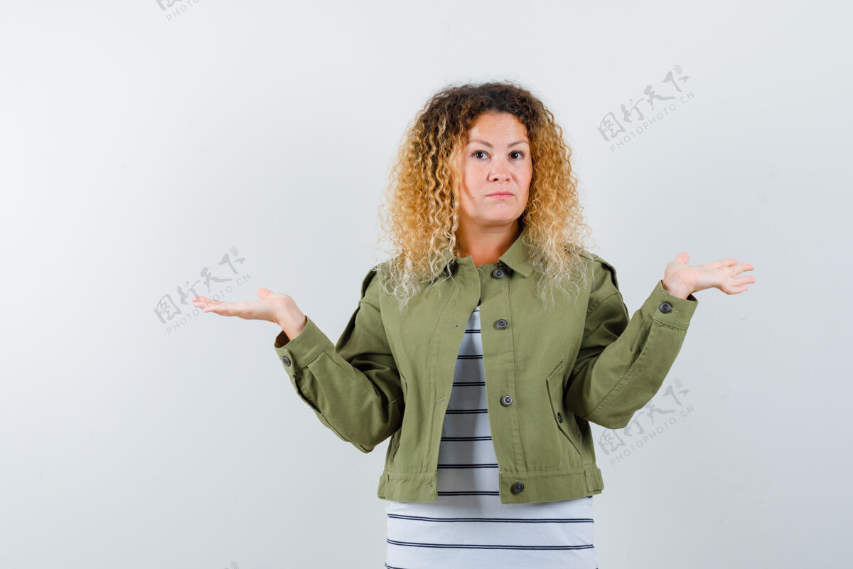 人一头卷曲的金发 穿着绿色夹克的女人 表现出无助的姿态和优柔寡断的神情 正面视图显示夹克评价