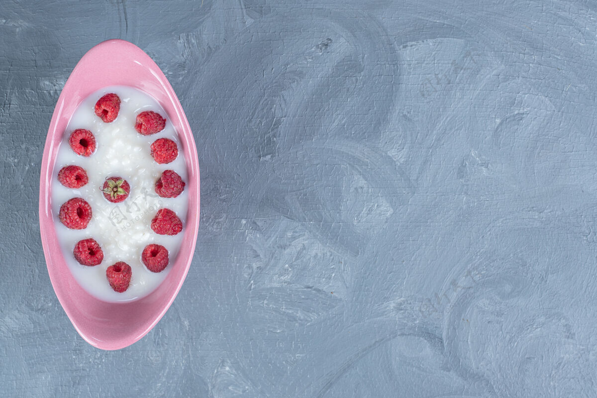 复制空间放在大理石桌上的粉红色碗里的米饭布丁 上面放着覆盆子美味背景水果