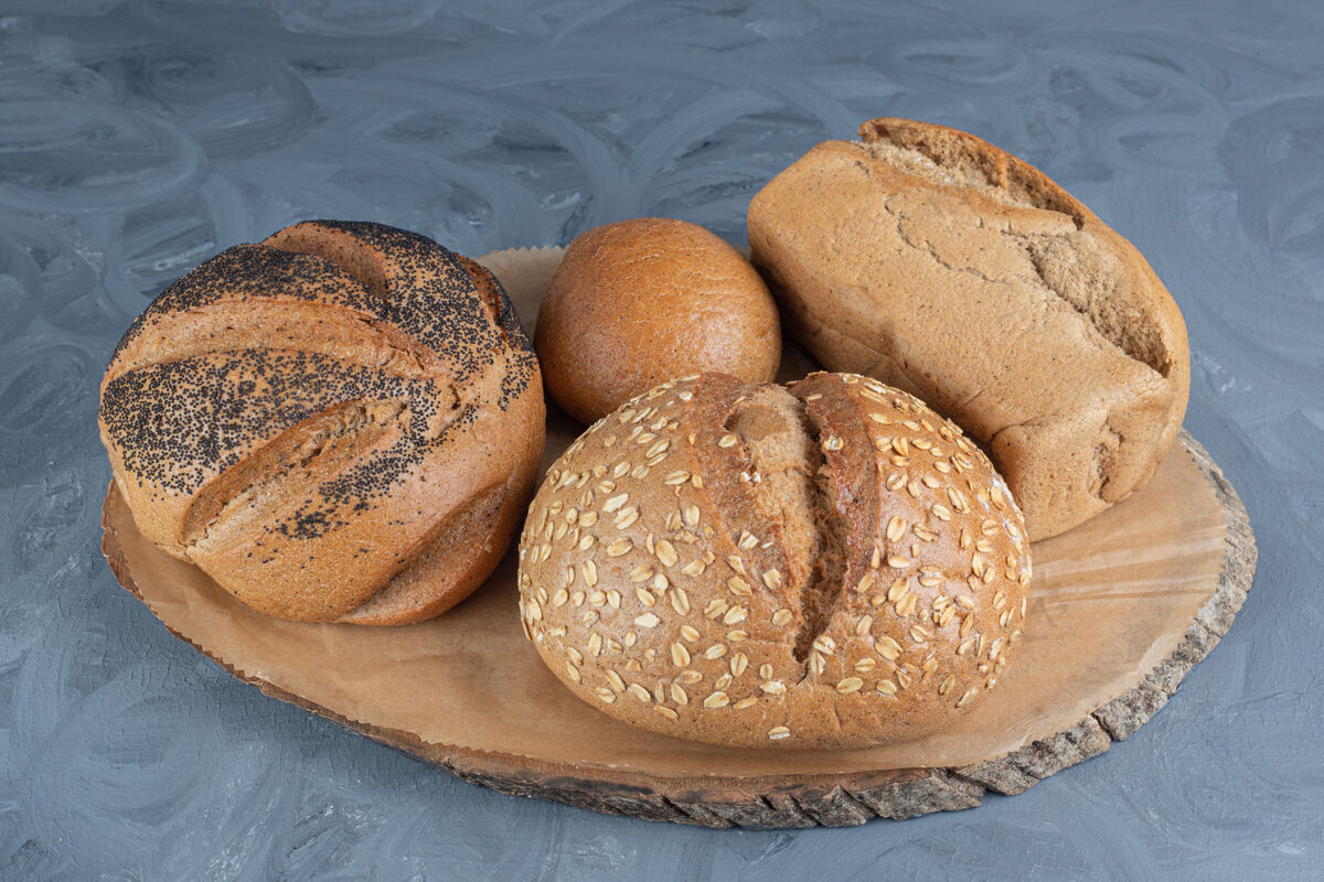 可口在大理石桌上的木板上放着各式各样的面包芝麻小麦面包屑