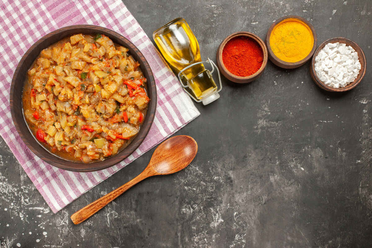 豆类顶视图烤茄子沙拉碗 油 木勺和不同的香料在黑暗的表面茄子沙拉蔬菜碗
