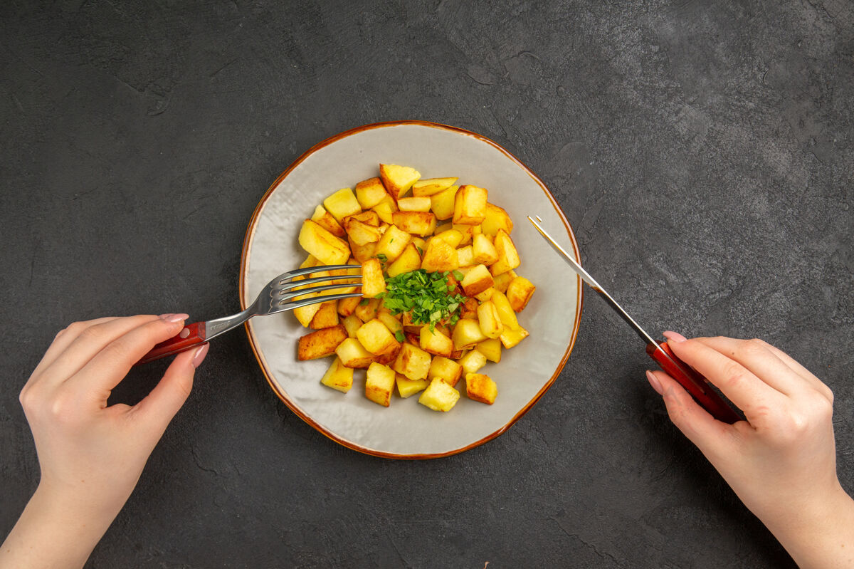 种子美味的炸土豆在黑暗的表面与绿色盘子里俯瞰蔬菜里面谷物
