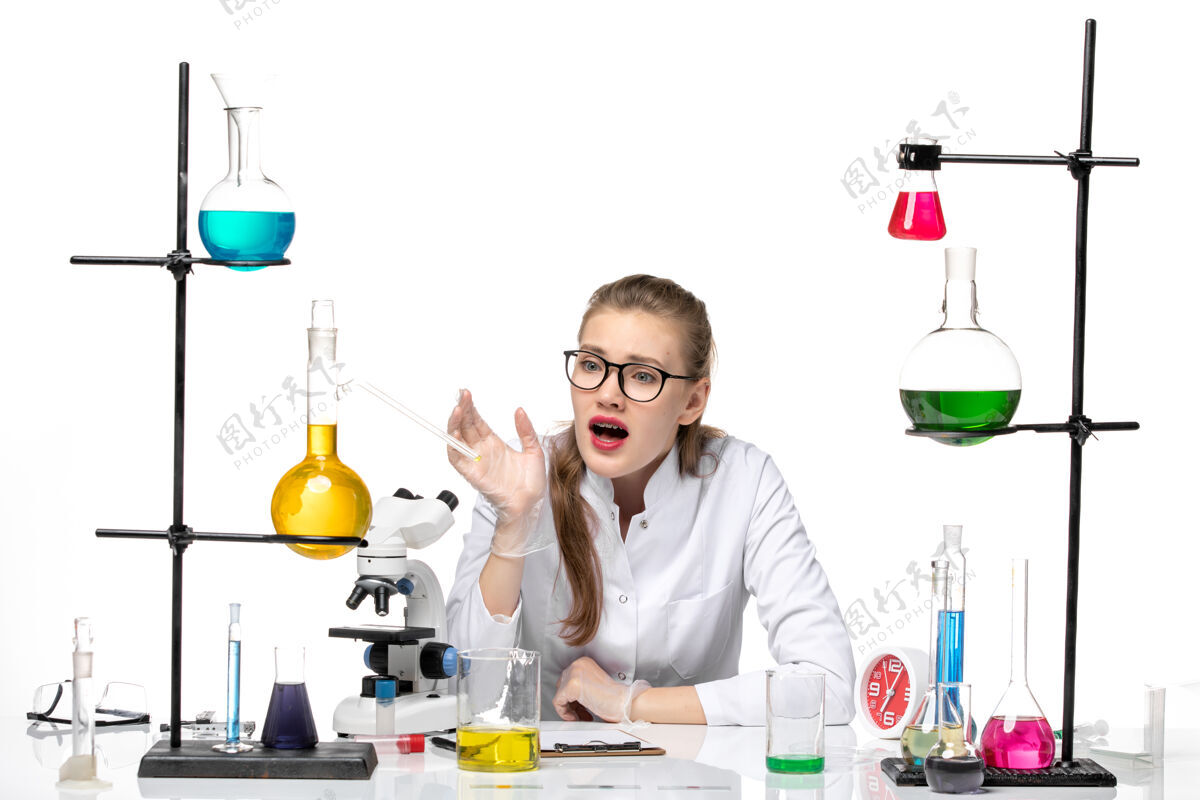 医学前视图：穿着医疗服的女化学家坐在白色背景上 拿着溶液大流行化学冠状病毒专业实验室医生
