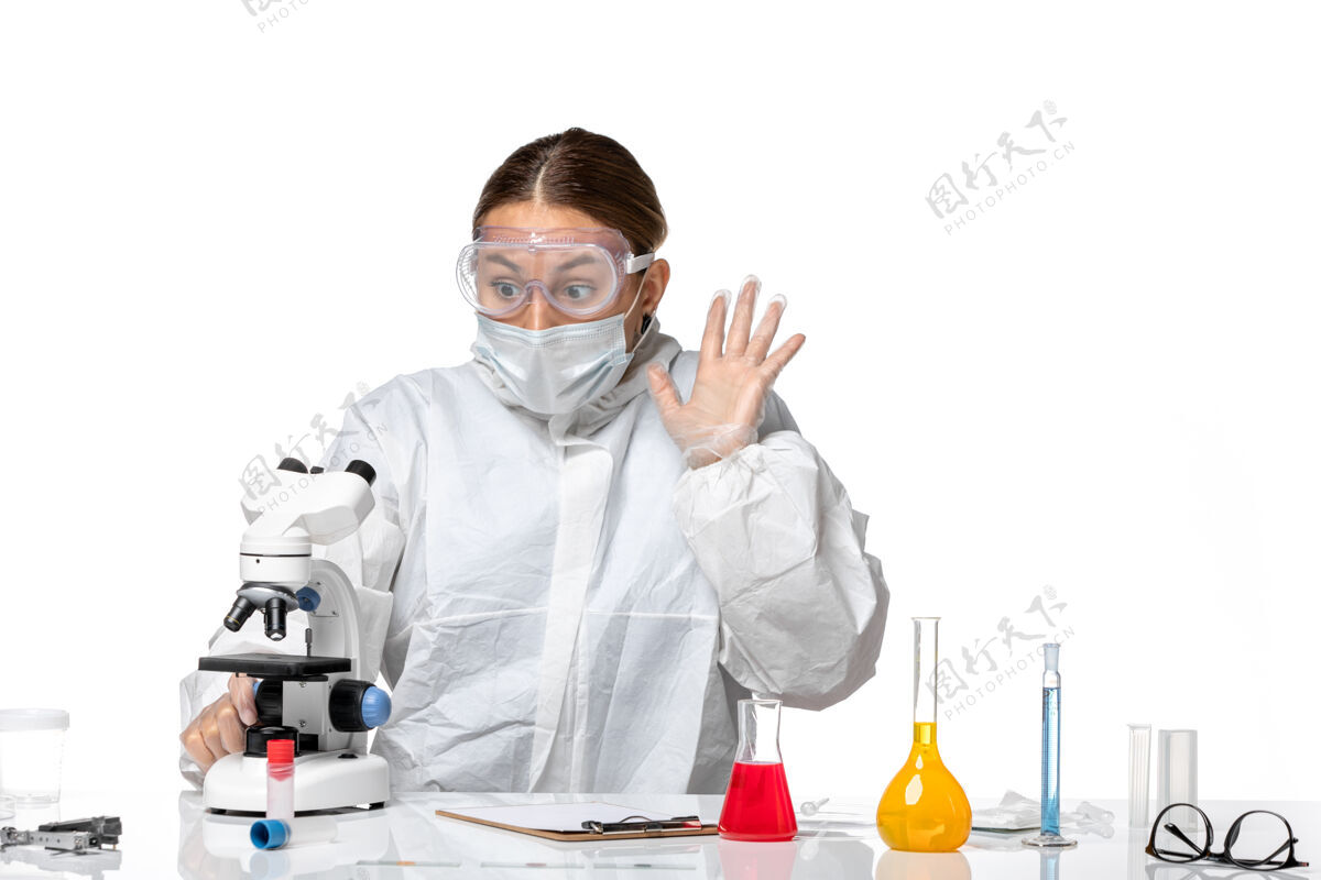 医学正面图女医生穿着防护服 戴着口罩 用显微镜观察淡白色背景上的健康大流行病毒冠状病毒显微镜专业使用