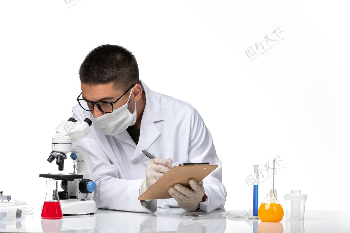病毒前视图穿着白色医疗服的男医生在白色空间里用显微镜工作健康人专业