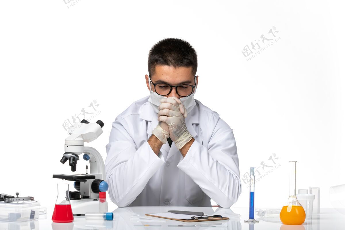 病毒正面图：男医生穿着白色医疗服 戴着面具 在一片空白中沉思大流行医学外套