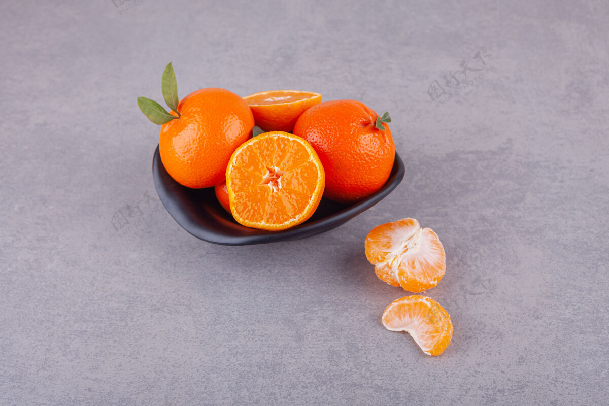 水果整个橘子和绿叶放在盘子里果汁异国风味食品